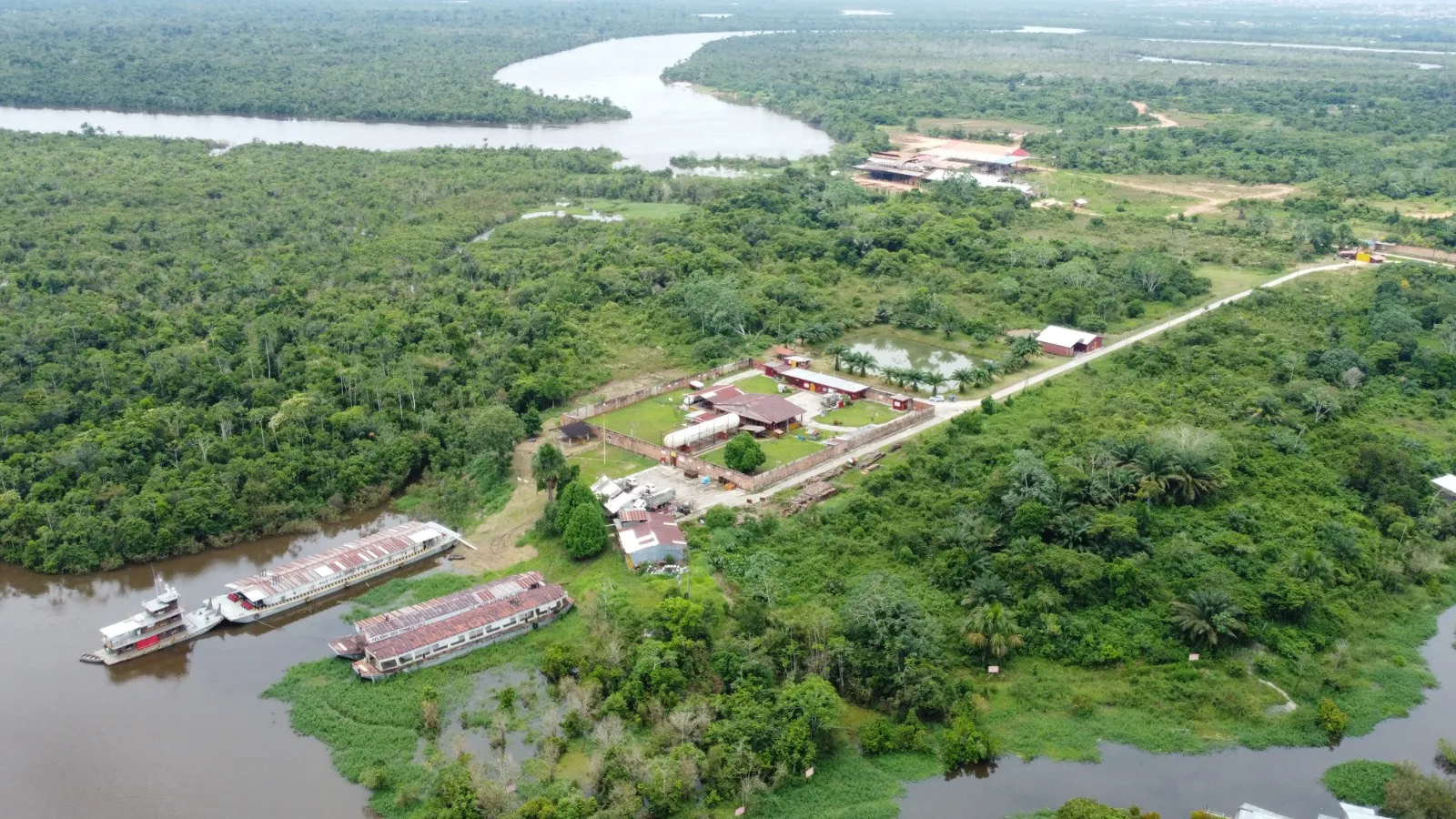 Vista aérea de la planta envasadora junto al río, con dos embarcaciones amarradas en el embarcadero