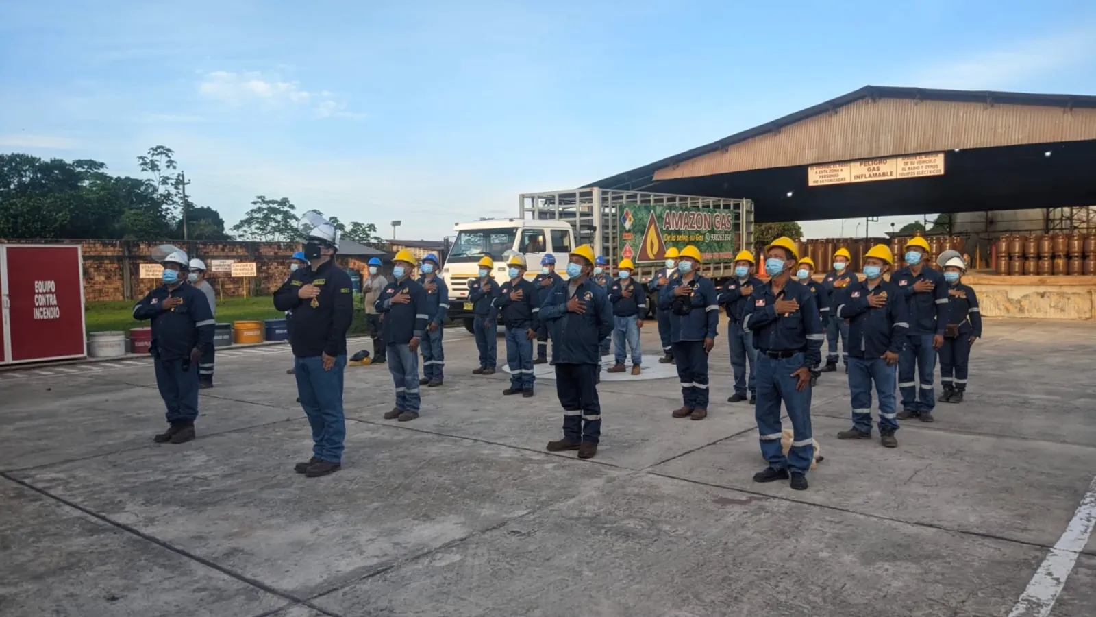 Personal de Amazon Gas con cascos y uniforme en formación frente a un camión de reparto en la planta