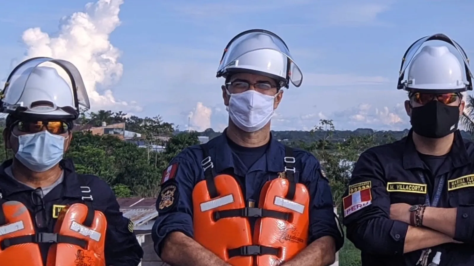Tres personas con chalecos salvavidas y cascos blancos frente al río